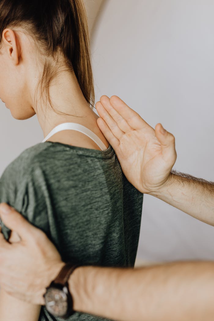 Side view of crop unrecognizable orthopedist in wristwatch examining anonymous woman in casual clothes in doctor office in hospital